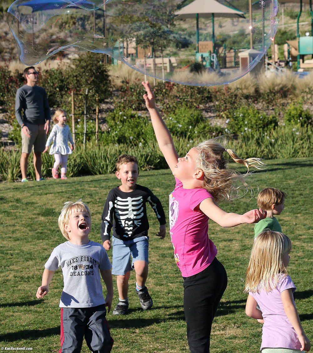 Katie reaches for a big bubble as Charlie watches.
