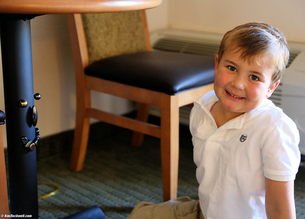Ryan mimicks the smiley face he made on the metal table support with his magnetic rocks, Furnace Creek Resort, Death Valley, California 8:34 AM.