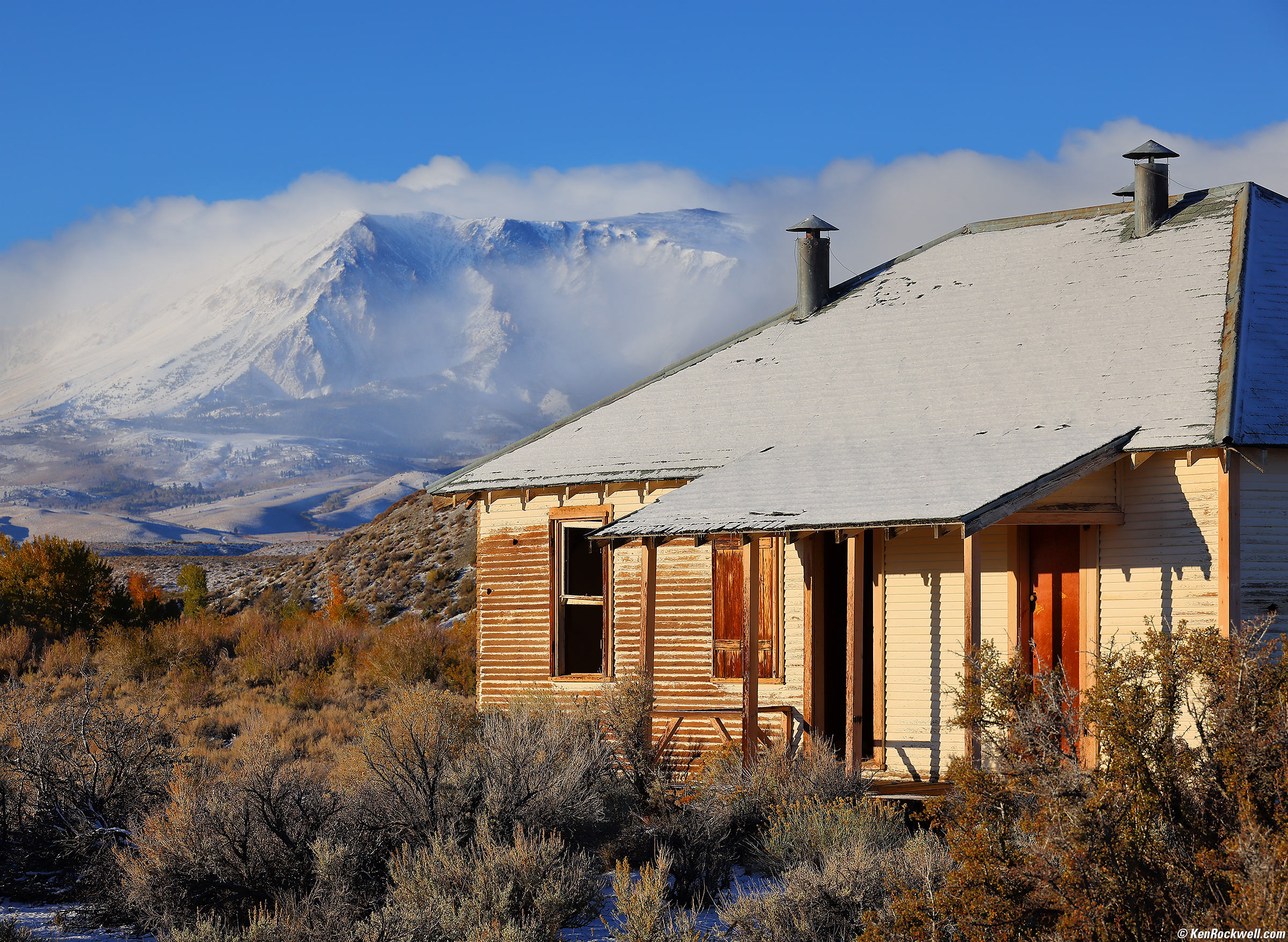 Abandoned shack with snowy mountains and Blowing Snow